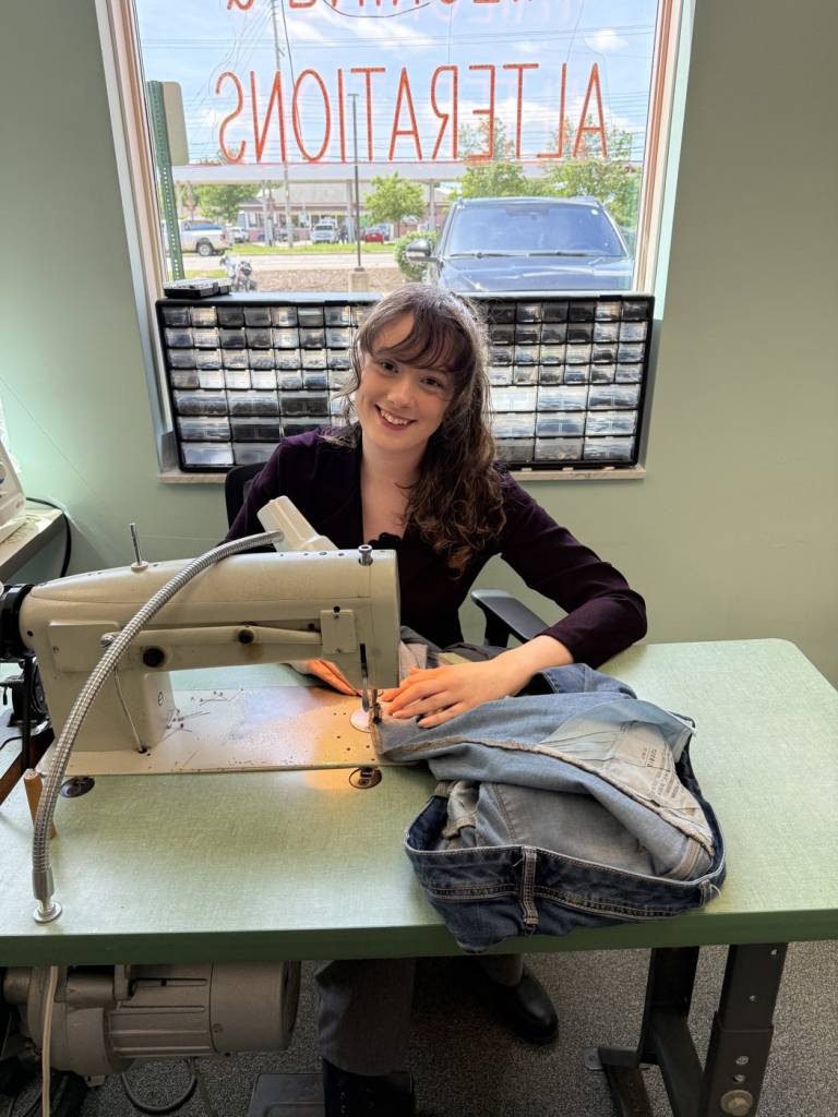 Miah, Baryames tailor, sewing at the Creyts and Saginaw store in West Lansing